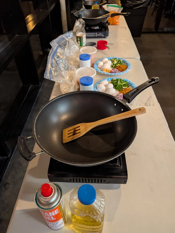 Cooking setup for an Authentic Pad Thai Class in San Diego, featuring ingredients and a wok on a table.