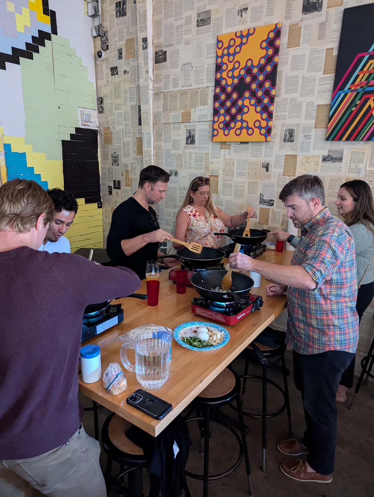 A group of people cooking together in a lively kitchen during an Authentic Pad Thai class in San Diego.