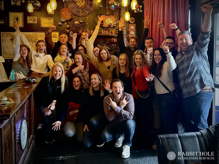 A diverse group of people celebrate together in an Escape Room in Denver, showing excitement and team spirit.