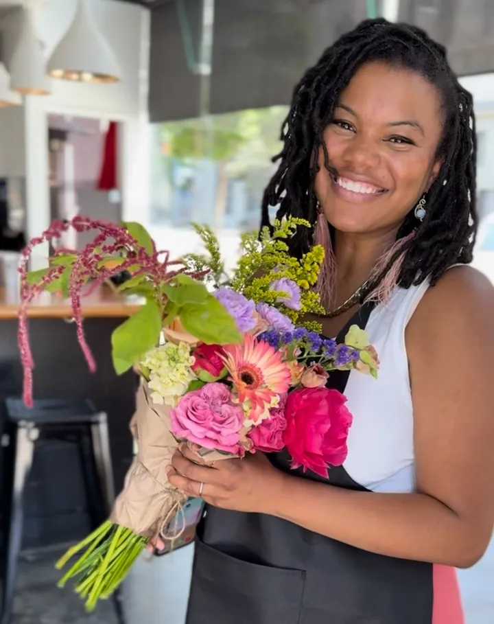 Smiling participant holding a colorful flower bouquet at a Floral Arranging Workshop in San Francisco.