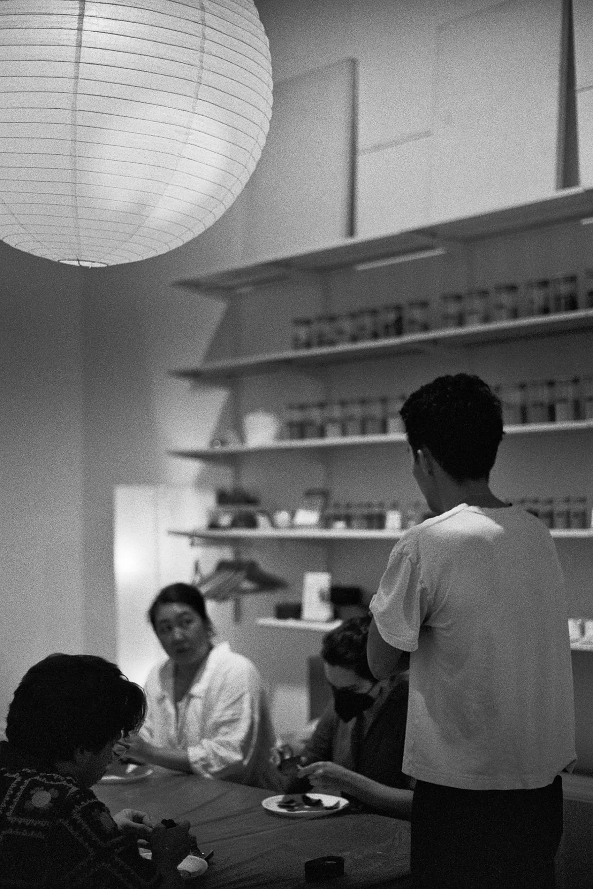 A Kintsugi class in Seattle, featuring participants engaged in conversation around a table with a Japanese lantern overhead.