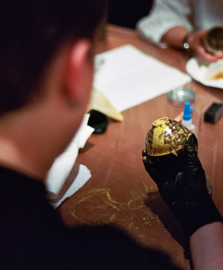 A participant in a Kintsugi class carefully holds a repaired ceramic bowl, highlighting collaboration and creativity.