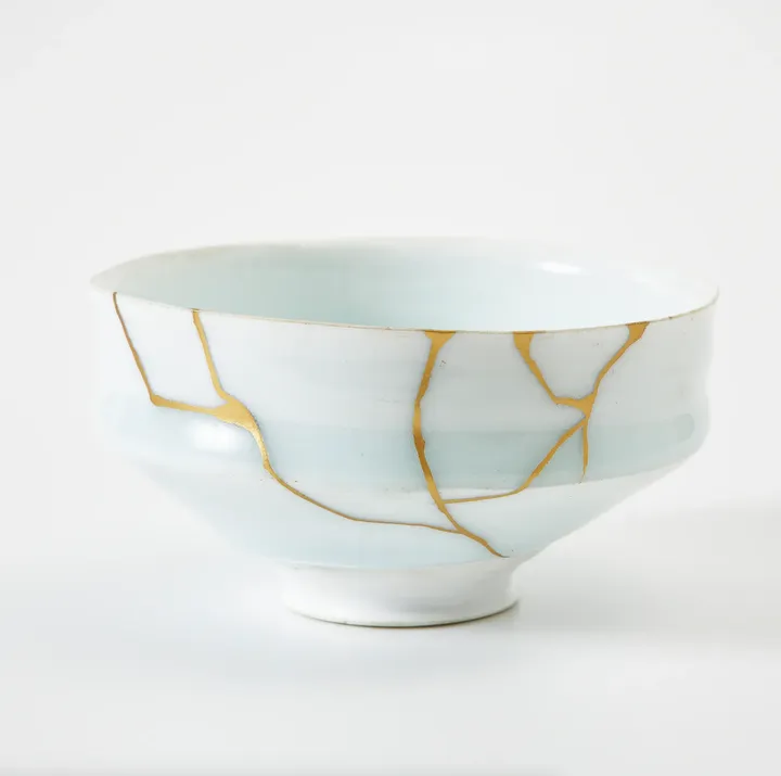 Ceramic bowl repaired with gold in Kintsugi style, showcasing a mix of blue and white colors.