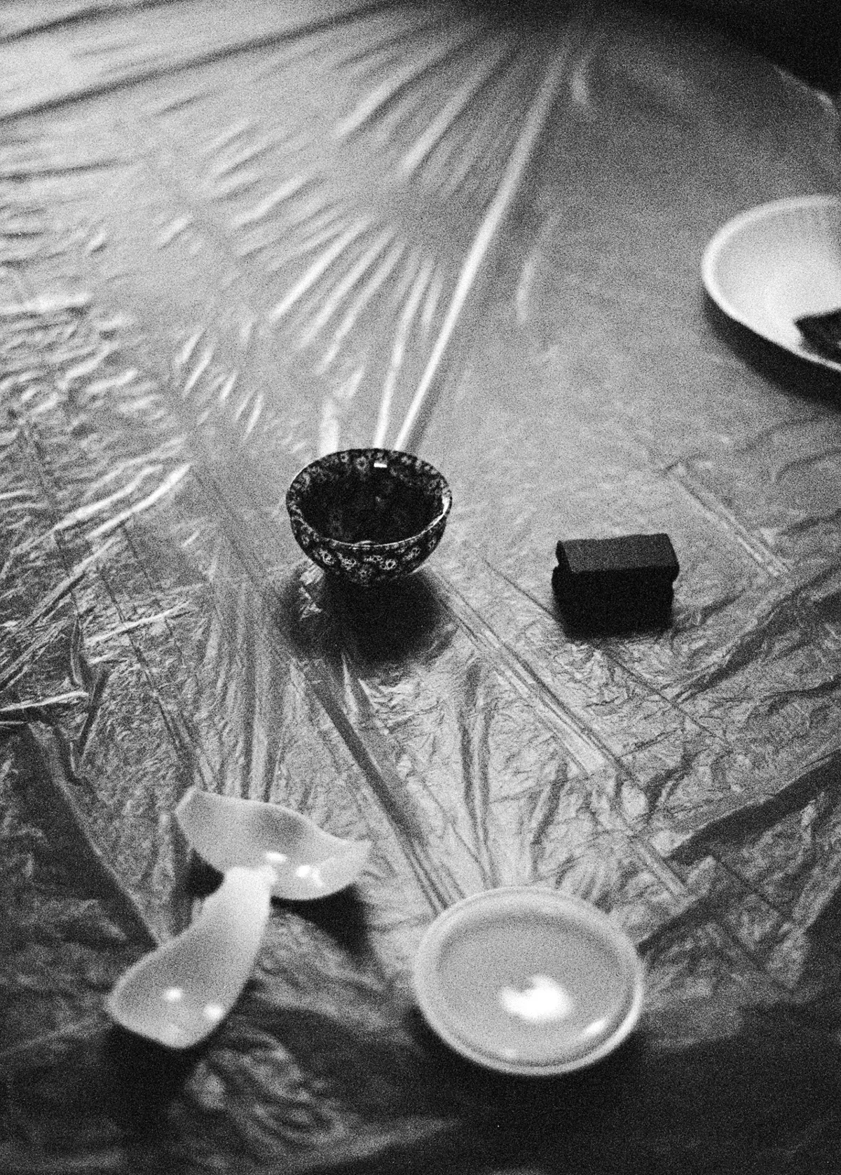 Kintsugi class materials arranged on a plastic-covered table, featuring broken pottery and adhesive.