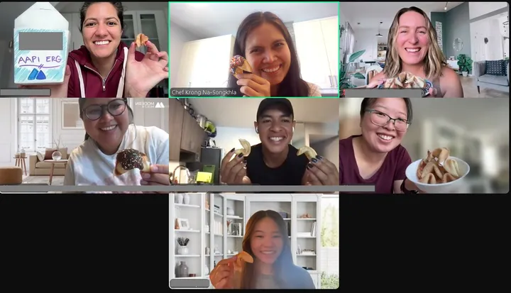 Participants in a virtual team-building activity hold homemade fortune cookies and share smiles in a video call.