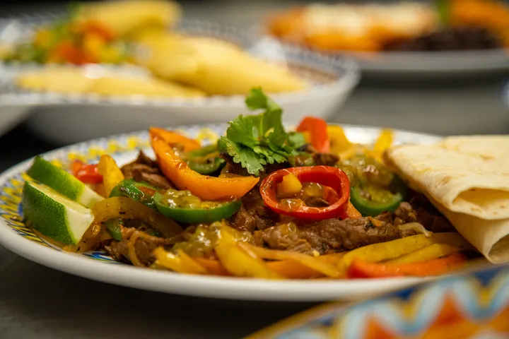 A vibrant plate of sizzling beef fajitas with colorful peppers, lime wedges, and tortillas. Perfect for a festive dinner.