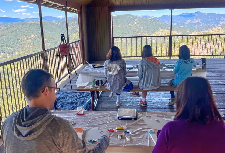 Group of people painting with a mountain view at the Mt. Falcon Hike and Paint team-building activity.