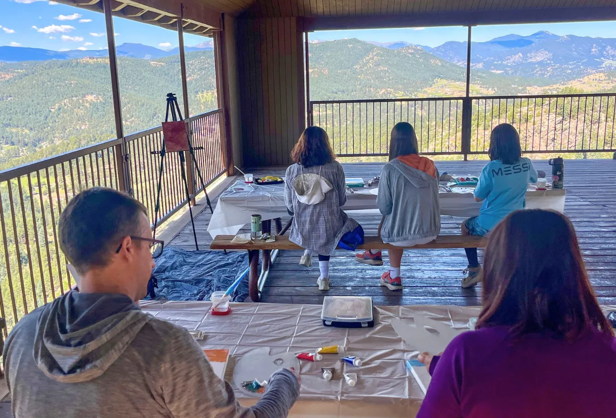 Participants enjoy painting with a scenic mountain view during a team-building hike and paint activity at Mt. Falcon.