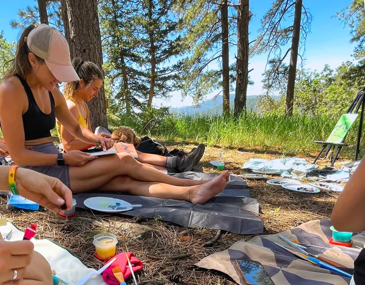 Participants enjoy painting in a serene forest setting during the Mt Falcon Hike and Paint activity in Denver.