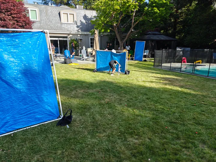 A yard set up for a Nerf Battle team-building activity, featuring blue barriers and participants preparing for the game.