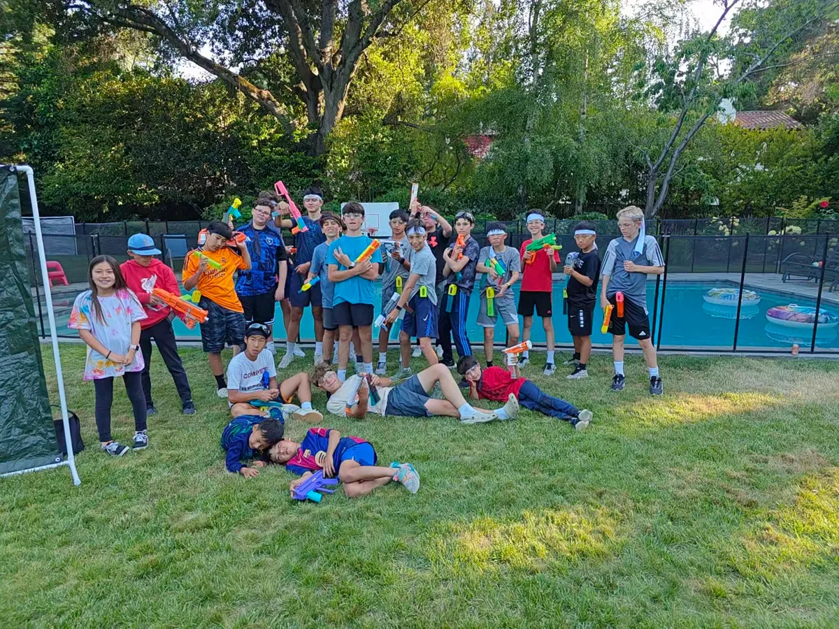 Group of participants in a Nerf Battle team-building activity, posing with Nerf blasters in a grassy area.