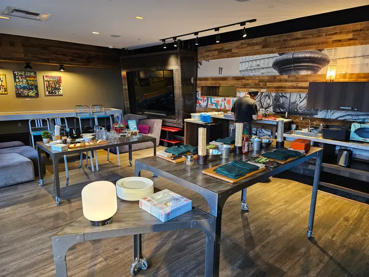 Bright workspace set up for a sushi-making workshop, featuring tables, ingredients, and a chef preparing food.