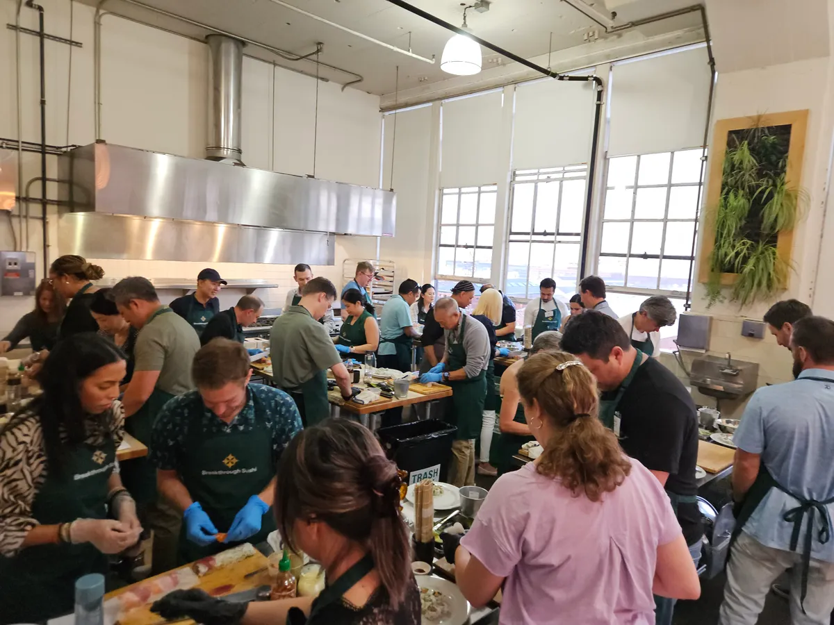 A busy sushi-making workshop in San Francisco with participants focused on preparing their dishes.