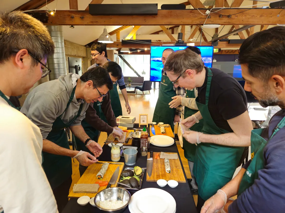 Participants in aprons engage in a sushi-making workshop, preparing rolls at a communal table in San Francisco.