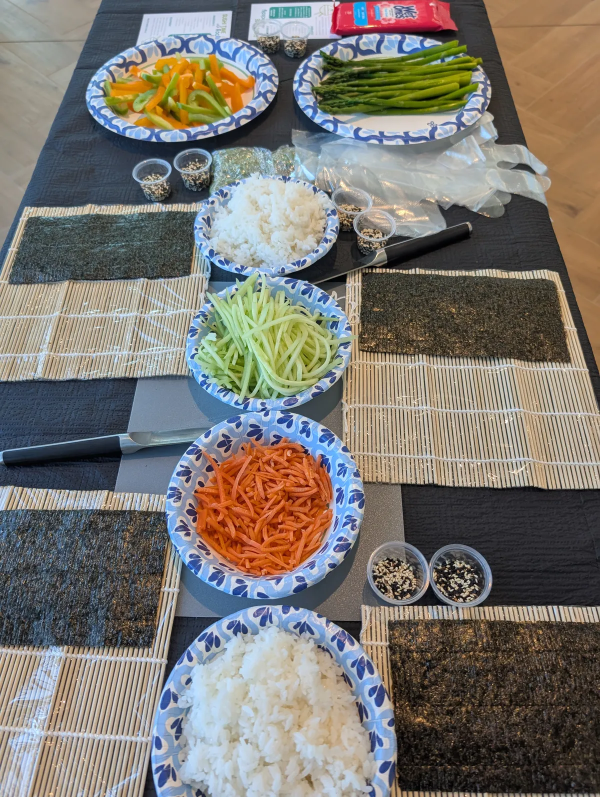 Ingredients for a sushi rolling class: colorful veggies, sliced cucumber, carrots, rice, nori, and sushi rolling mats.