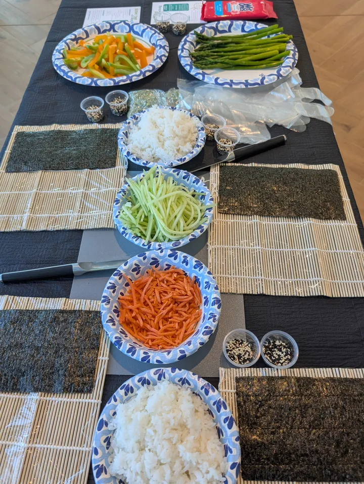 Ingredients for a sushi rolling class: colorful veggies, sliced cucumber, carrots, rice, nori, and sushi rolling mats.