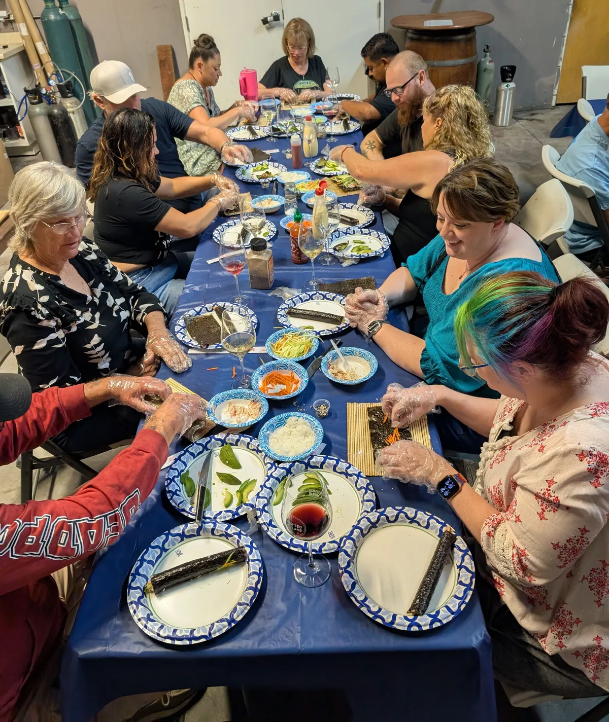 Group of participants at a Sushi Rolling Class in San Diego, creating sushi at a long table filled with ingredients.