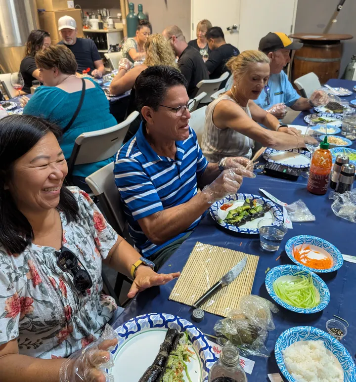 Participants enjoy a sushi rolling class in San Diego, preparing sushi with fresh ingredients and laughter.