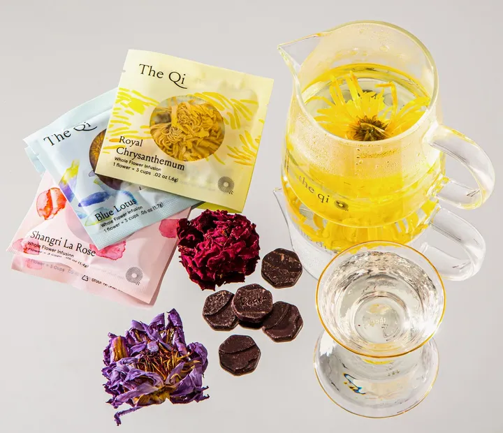 Tea and chocolate pairing setup featuring colorful flower teas, chocolate pieces, and a glass pitcher in NYC.