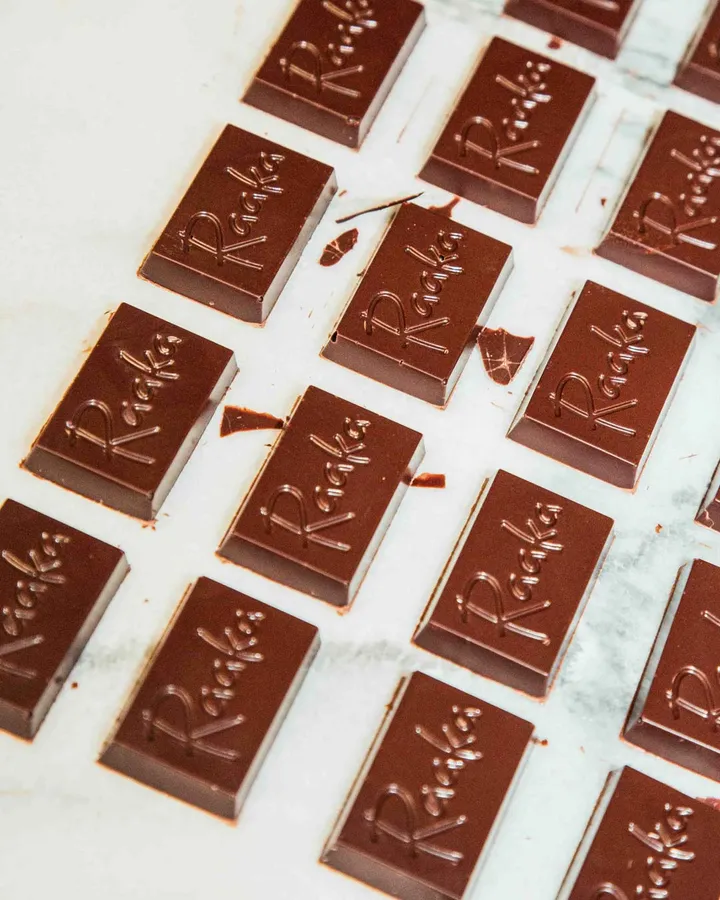 Close-up of Raaka chocolate bars neatly arranged on a marble surface for a tea and chocolate pairing activity.