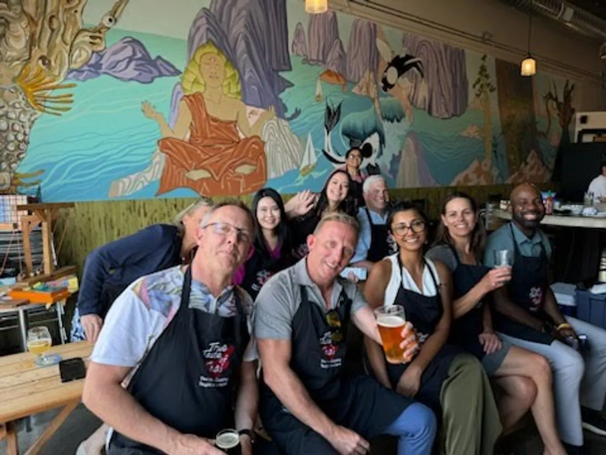 A group of participants enjoys a Thai Red Curry cooking class in San Diego, smiling and posing together.