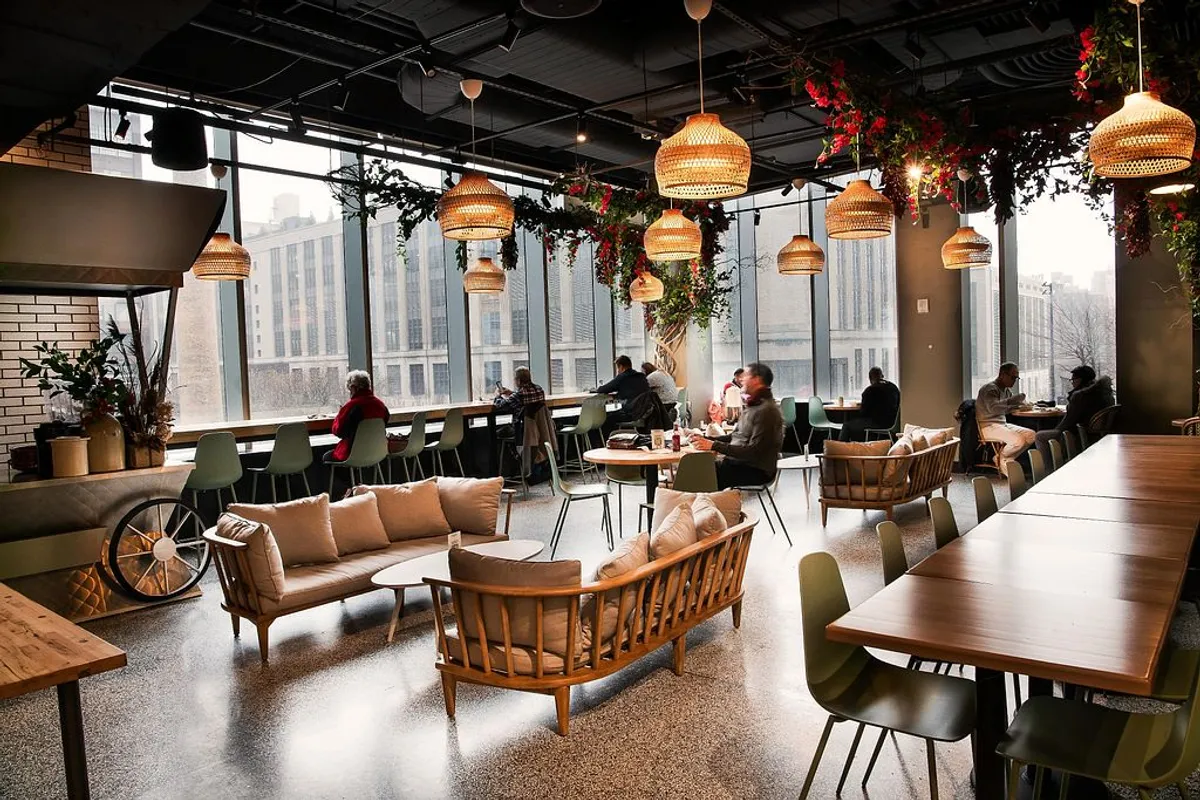 Bright, modern venue with comfortable seating, plants, and large windows, filled with patrons enjoying a food tour.