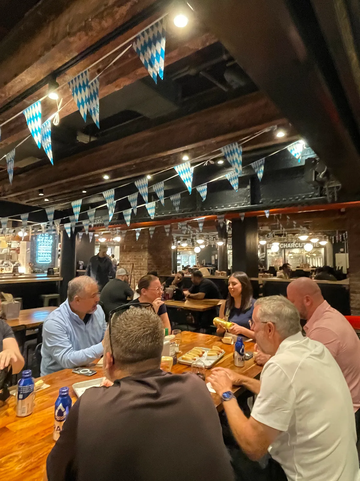 Team members enjoy a seated food tour in a lively NYC venue, sharing food and conversation under festive decorations.